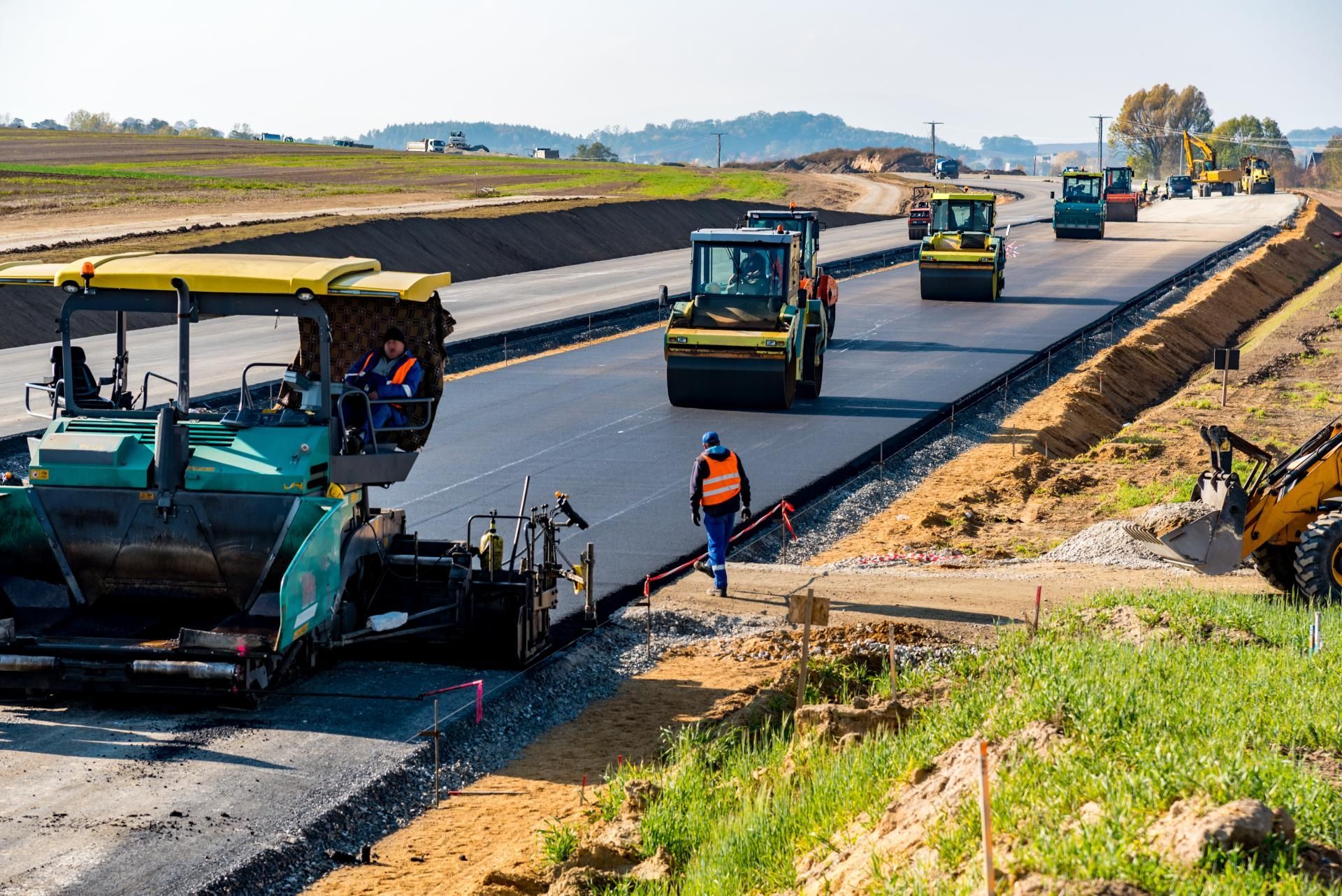 Eine Gruppe von Baufahrzeugen arbeitet an einer im Bau befindlichen Autobahn.