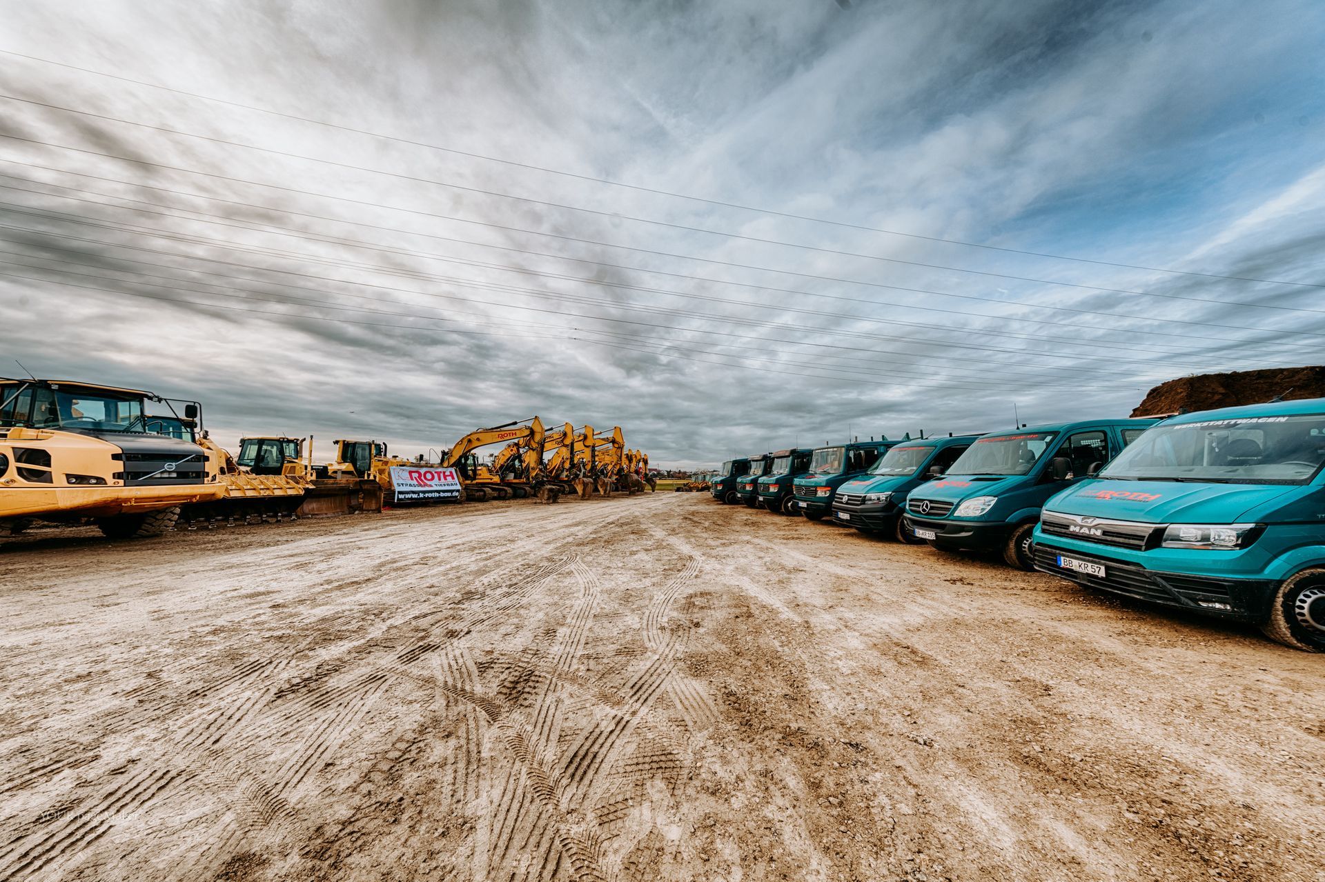 Eine Reihe von Baufahrzeugen ist auf einem Feld geparkt.