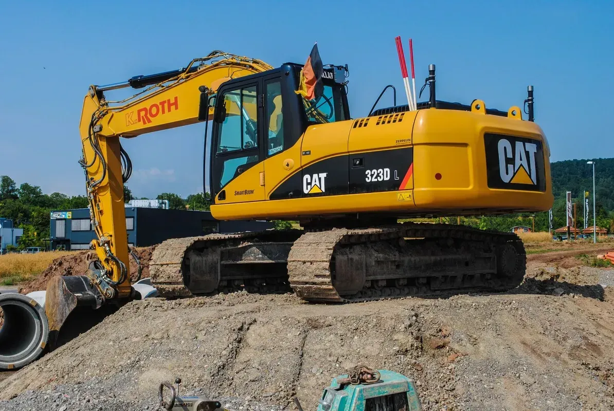 Ein gelber Cat-Bagger steht auf einem Erdhaufen.