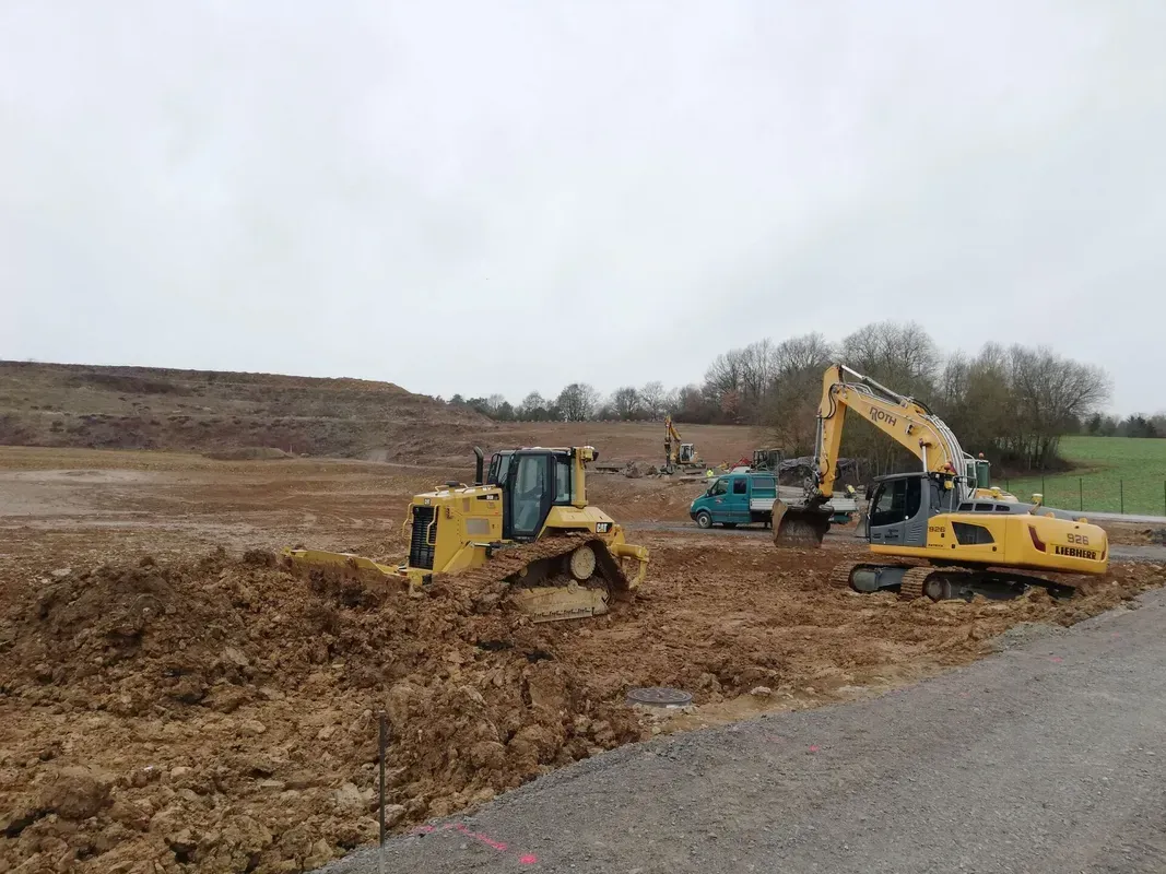 Eine Planierraupe und ein Bagger arbeiten auf einem Feld.