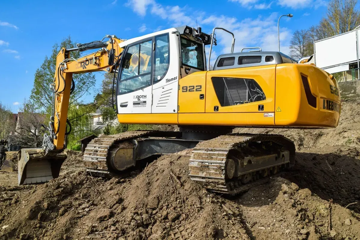 Ein großer gelber Bagger steht auf einem Erdhaufen.