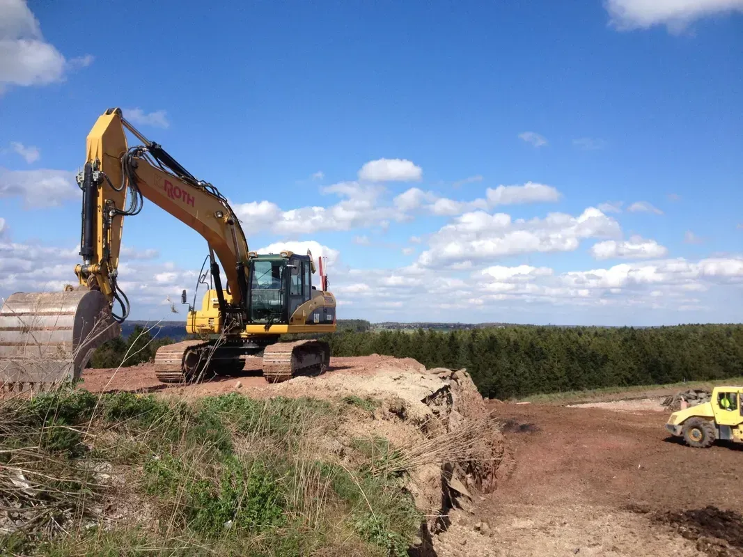 Ein gelber Bagger steht auf einem Erdhügel.