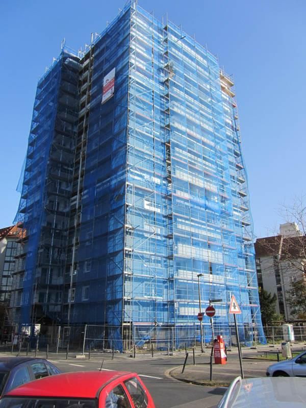 Ein hohes Gebäude mit blauen Gerüsten drumherum