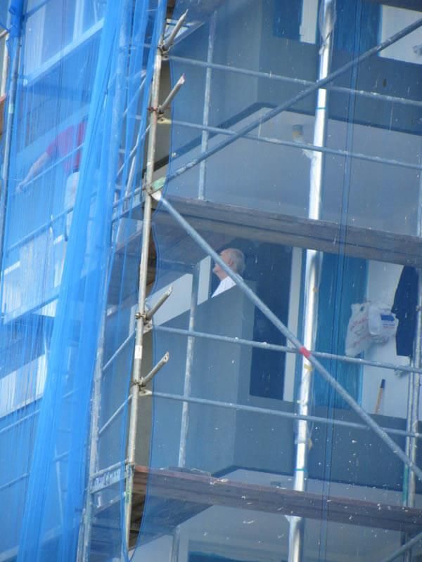 Ein Mann schaut aus einem Fenster hinter einem Gerüst