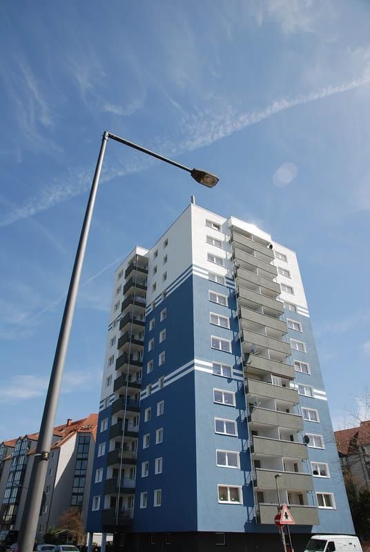 Ein hohes blau-weißes Gebäude mit einer Straßenlaterne davor