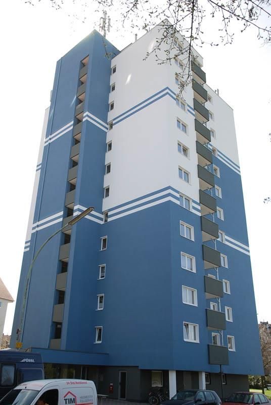 Ein blau-weißes Gebäude mit einem davor geparkten weißen Lieferwagen