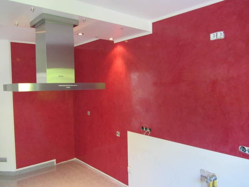 Eine Küche mit roten Wänden und einer Dunstabzugshaube aus Edelstahl