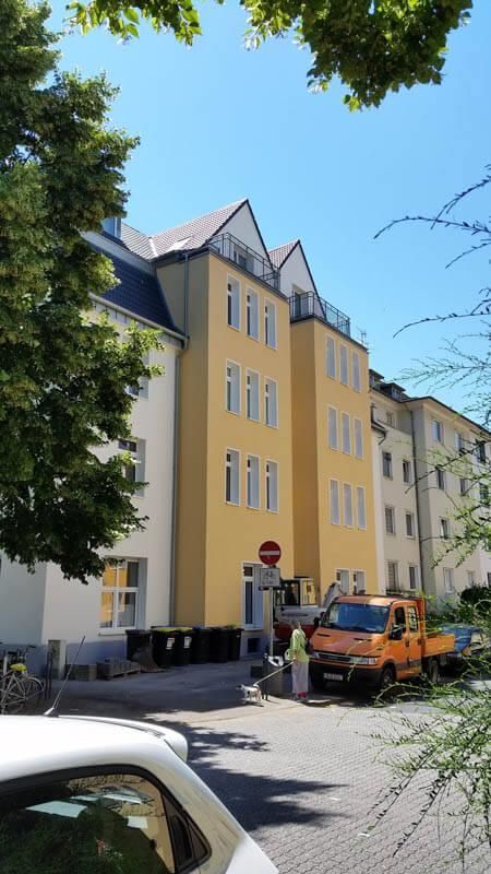 Ein weißes Auto parkt vor einem gelben Gebäude