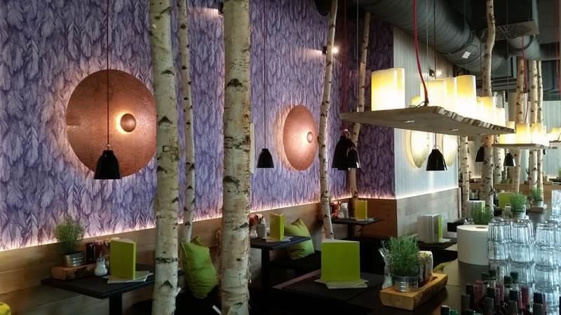 Ein Restaurant mit Tischen und Stühlen und einer violetten Wand.