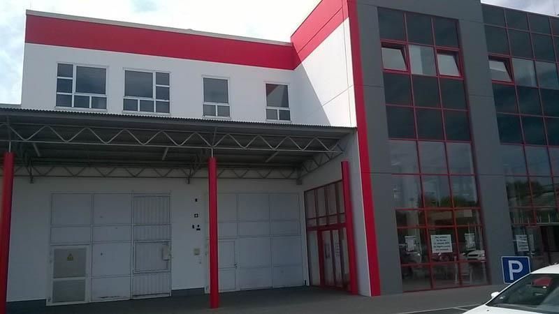 Ein rot-weißes Gebäude mit einem davor geparkten Auto