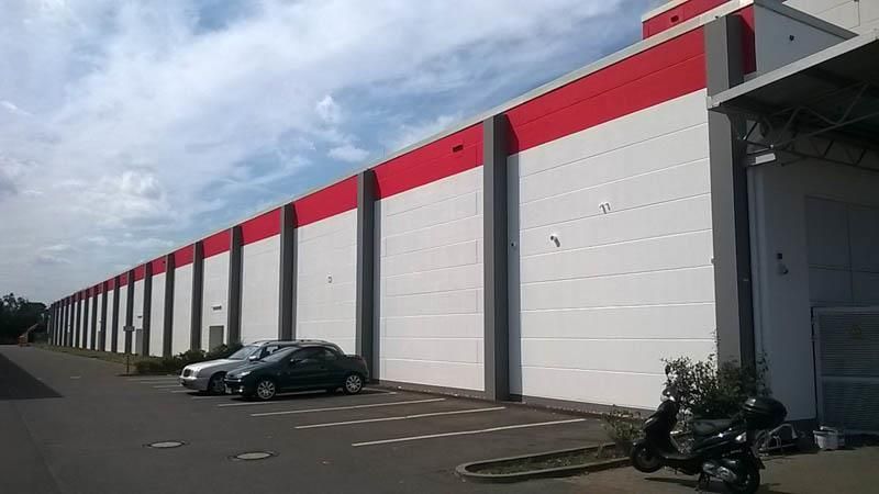 Vor einem großen Gebäude parkt eine Reihe Autos.