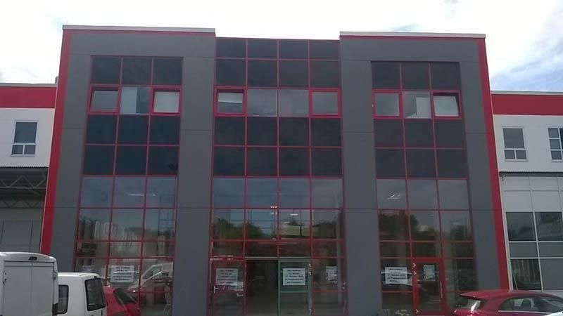 Ein großes Gebäude mit vielen Fenstern und davor geparkten Autos.