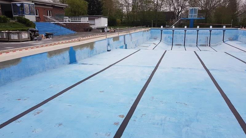 Ein leeres Schwimmbecken mit einem Sprungturm im Hintergrund