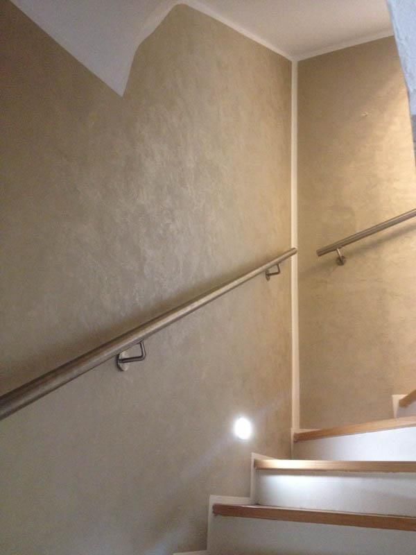 Eine Treppe mit Geländer und Licht auf der untersten Stufe.