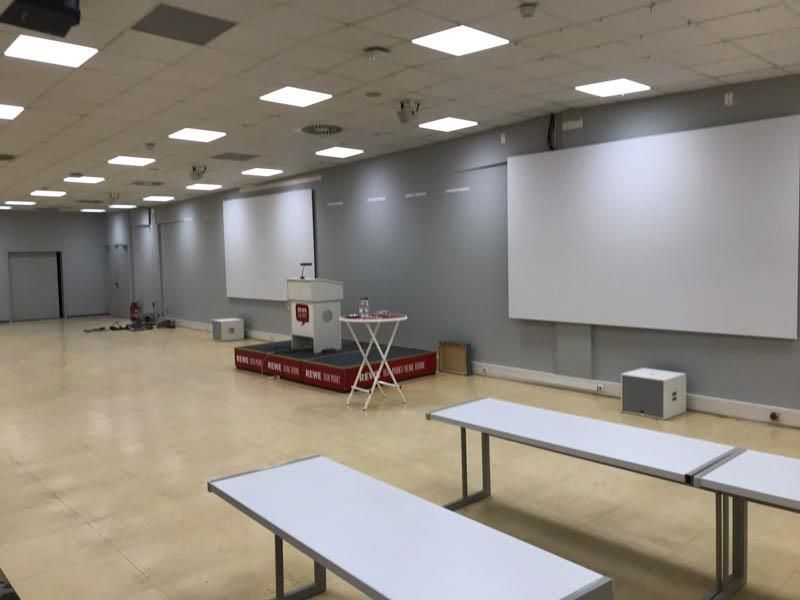 Ein großer Raum mit Tischen und Projektionsleinwänden