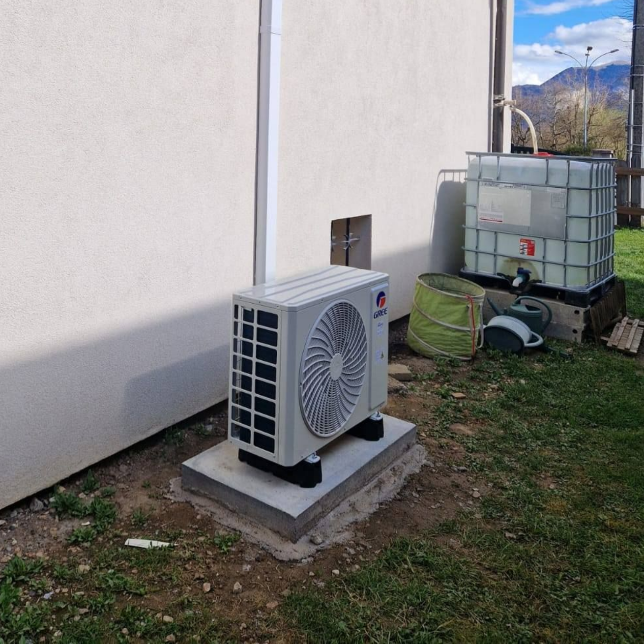 Unité de pompe à chaleur blanche et un réservoir d'eau à l'arrière d'une maison.