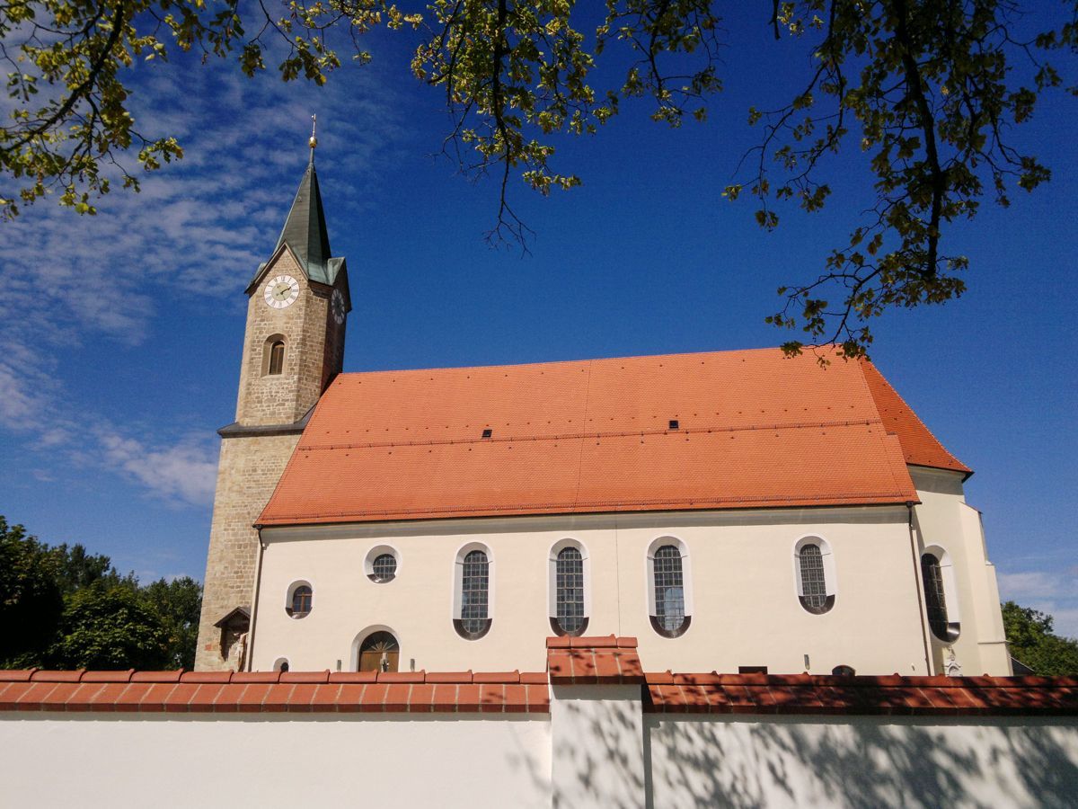 Außenansicht der Pfarrkirche - Kleiner Turm in Steinoptik und großes Langhaus in warmen Farben gehalten