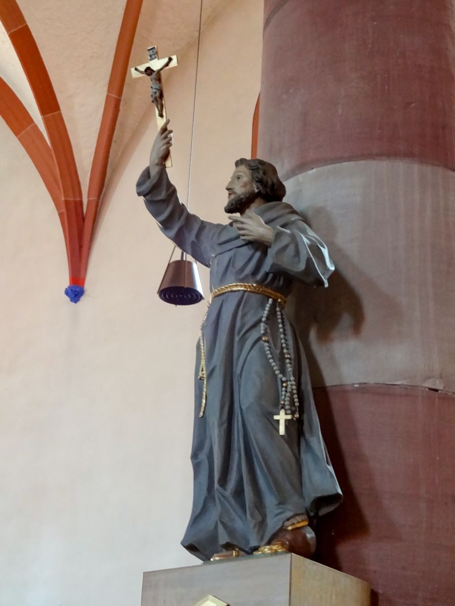 Hl. Franziskus steht mit einem Fuß auf dem Geldsack als Abwertung für alles Materielle