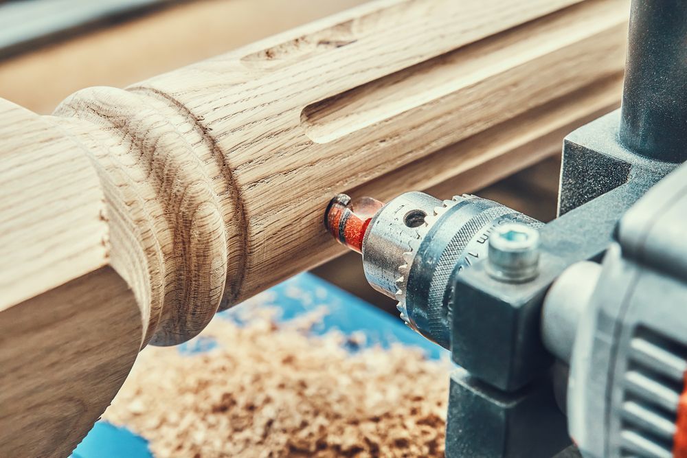 Un taladro está cortando un agujero en un trozo de madera.