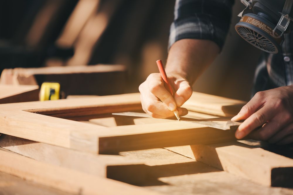 Un hombre está midiendo un trozo de madera con una regla y un lápiz.