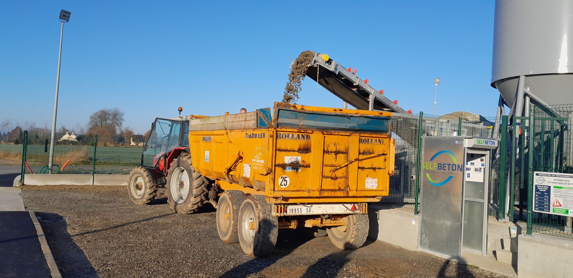 Une remorque de benne jaune qui se fait remplir de béton