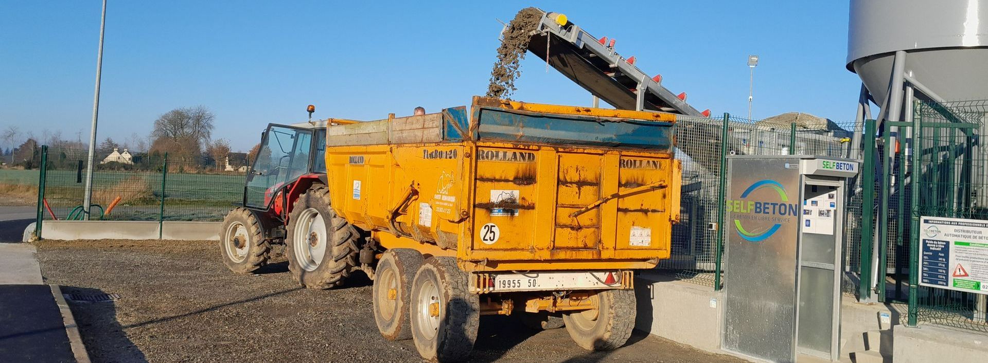 Un camion-benne jaune qui se fait charger en béton