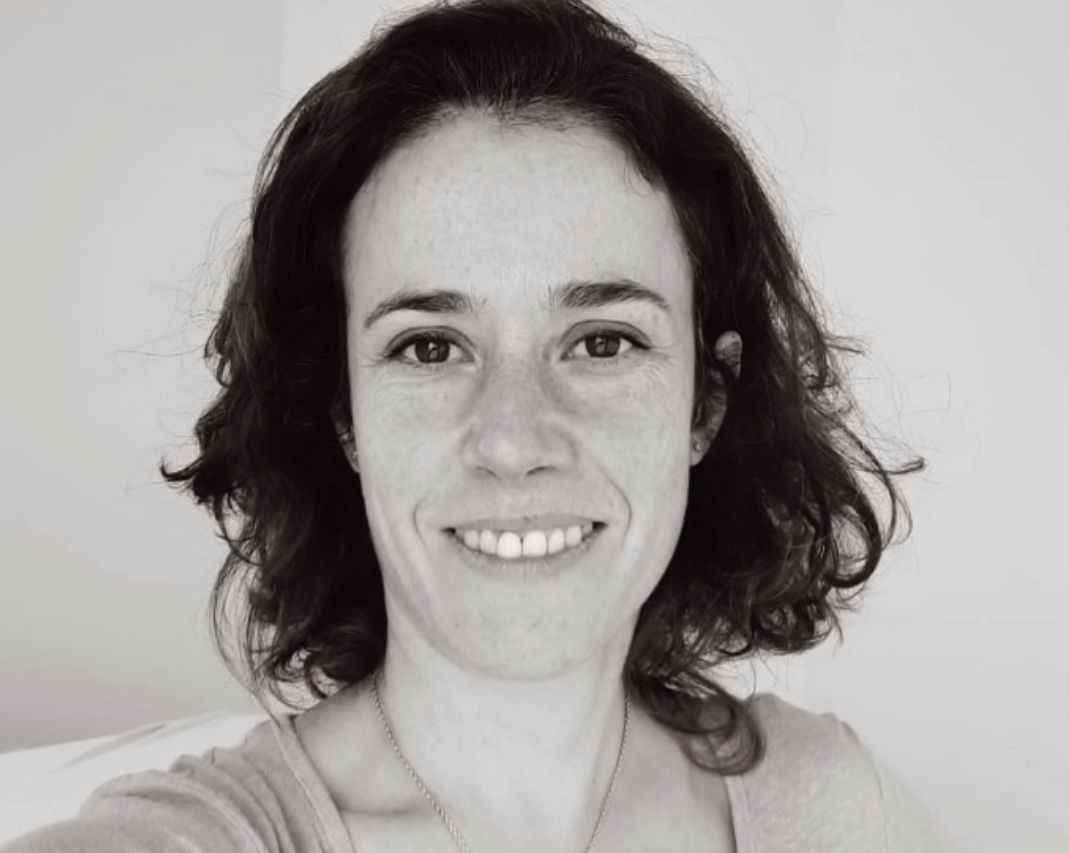 Une femme qui sourit et avec des cheveux fonçés mi-longs