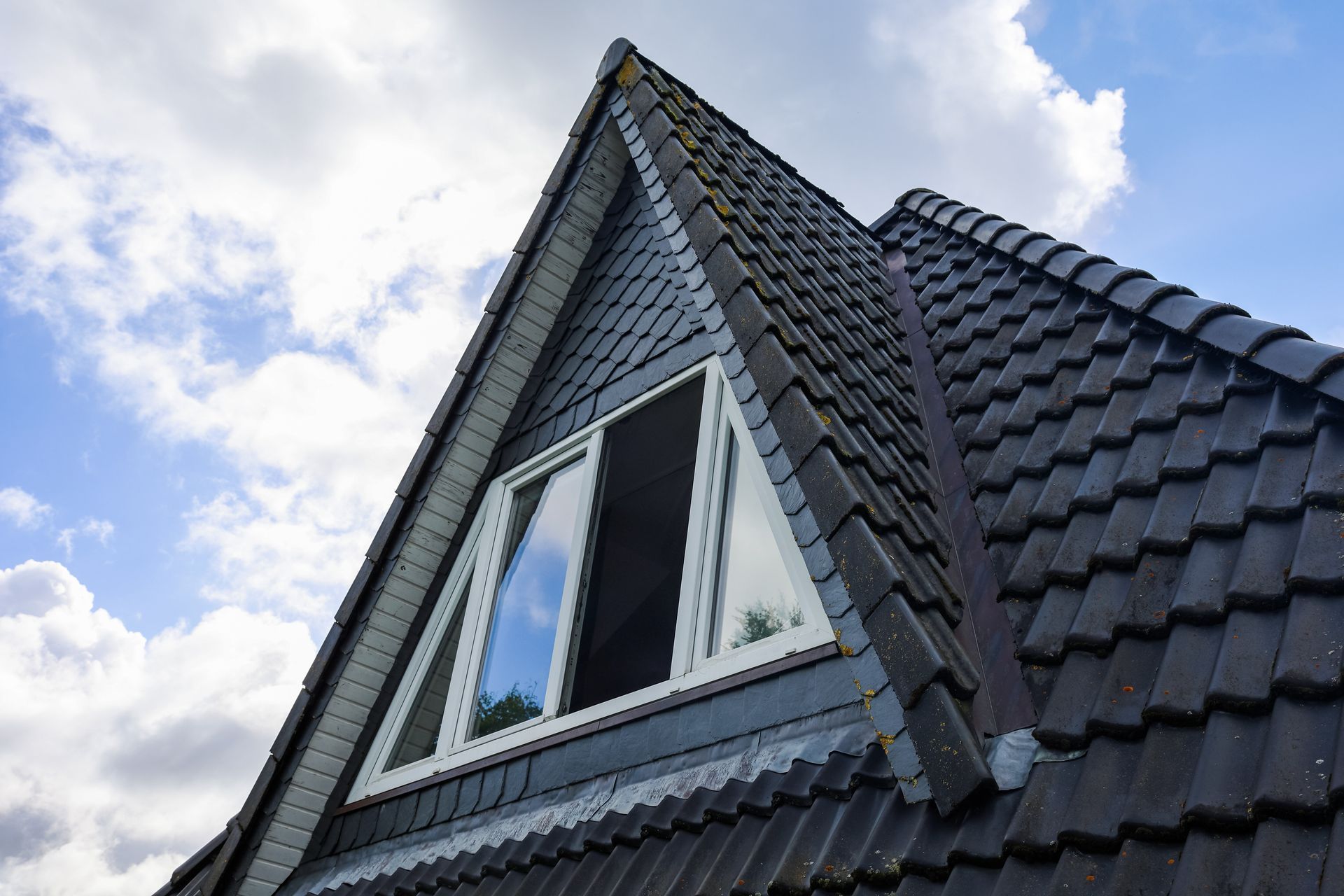 Toit d’une maison moderne avec une lucarne triangulaire.