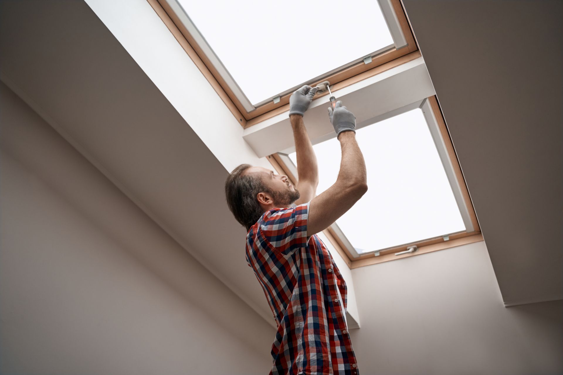 Personne qui installe une fenêtre de toit au plafond avec des outils.