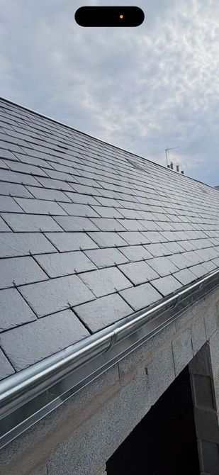 Gros plan sur le toit d’une maison, avec des gouttières et un soffite.