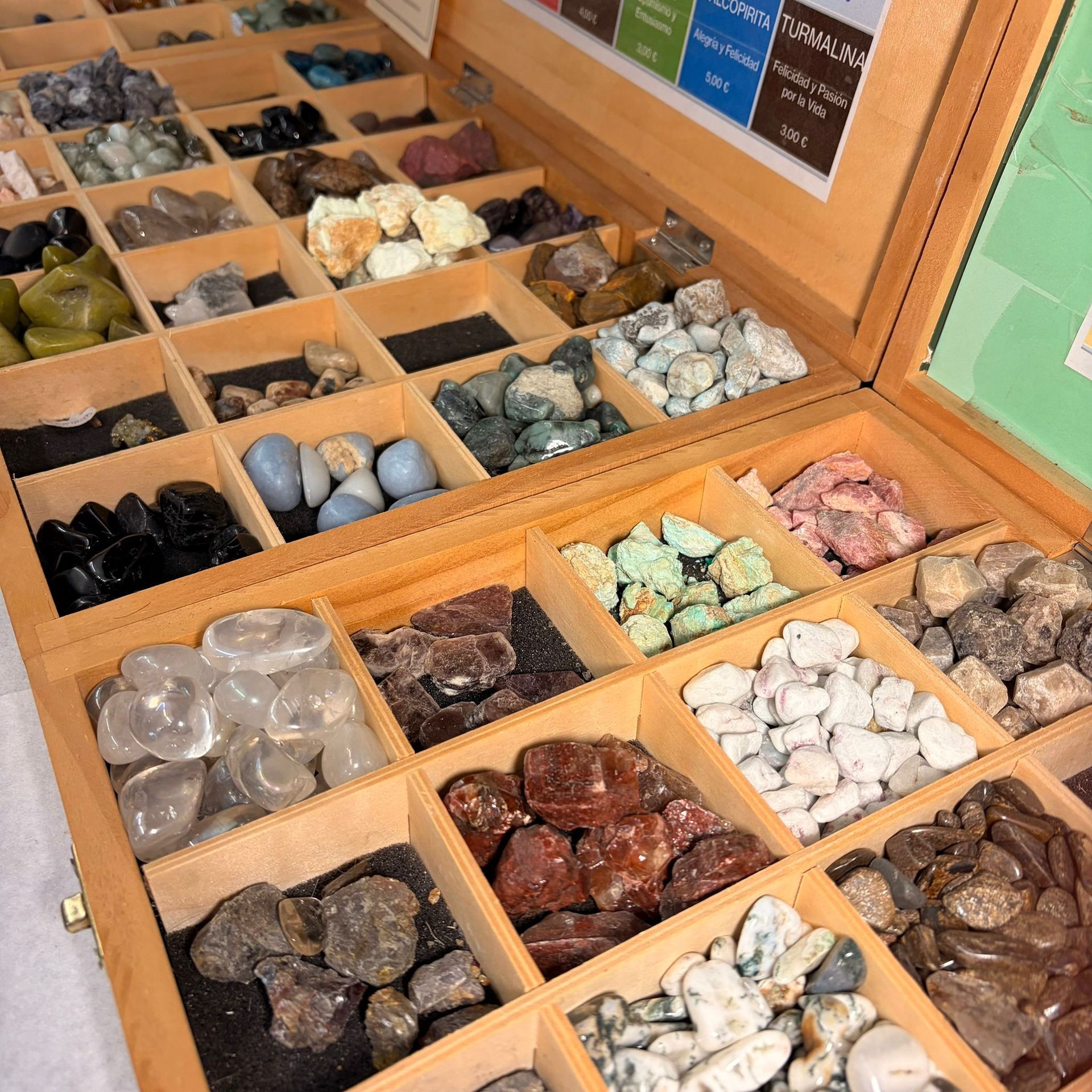 Caja de exhibición de madera llena de varias piedras preciosas y cristales de colores.