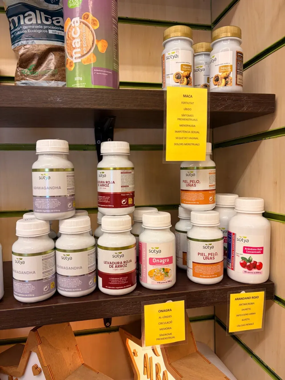 Estantes repletos de diversas botellas de suplementos blancos, algunas con etiquetas amarillas, en un entorno de tienda.