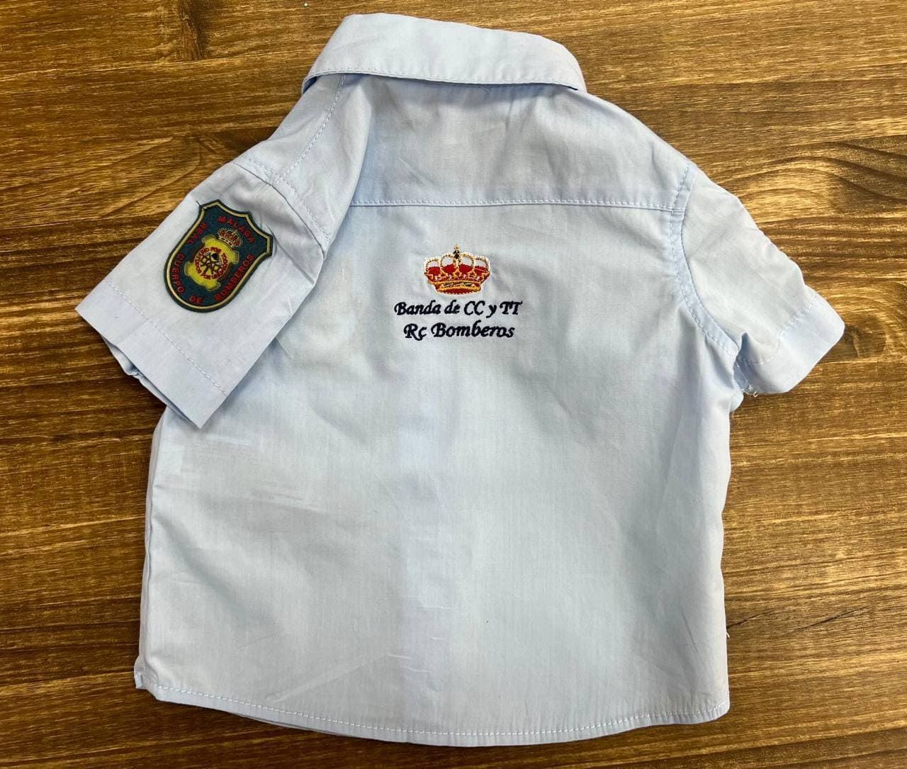 La parte trasera de una camisa azul claro con una insignia en la manga.