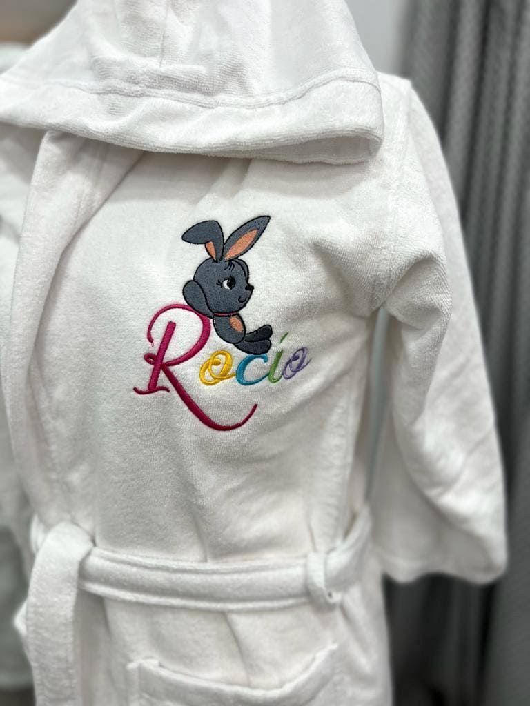 Una túnica blanca con un conejito bordado.