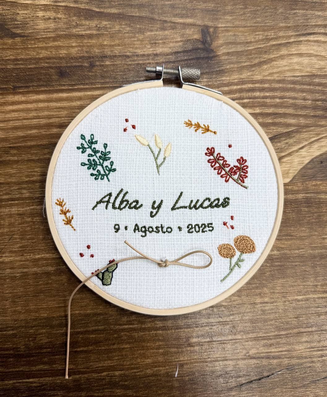 Un bastidor de bordado está sobre una mesa de madera.