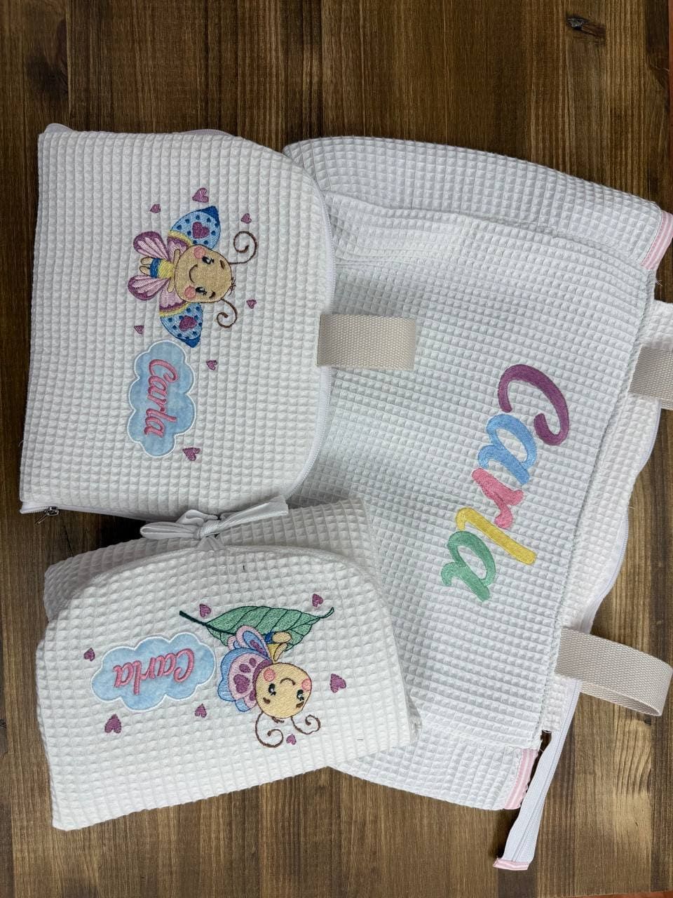 Una toalla blanca con el nombre Carla bordado está sobre una mesa de madera.