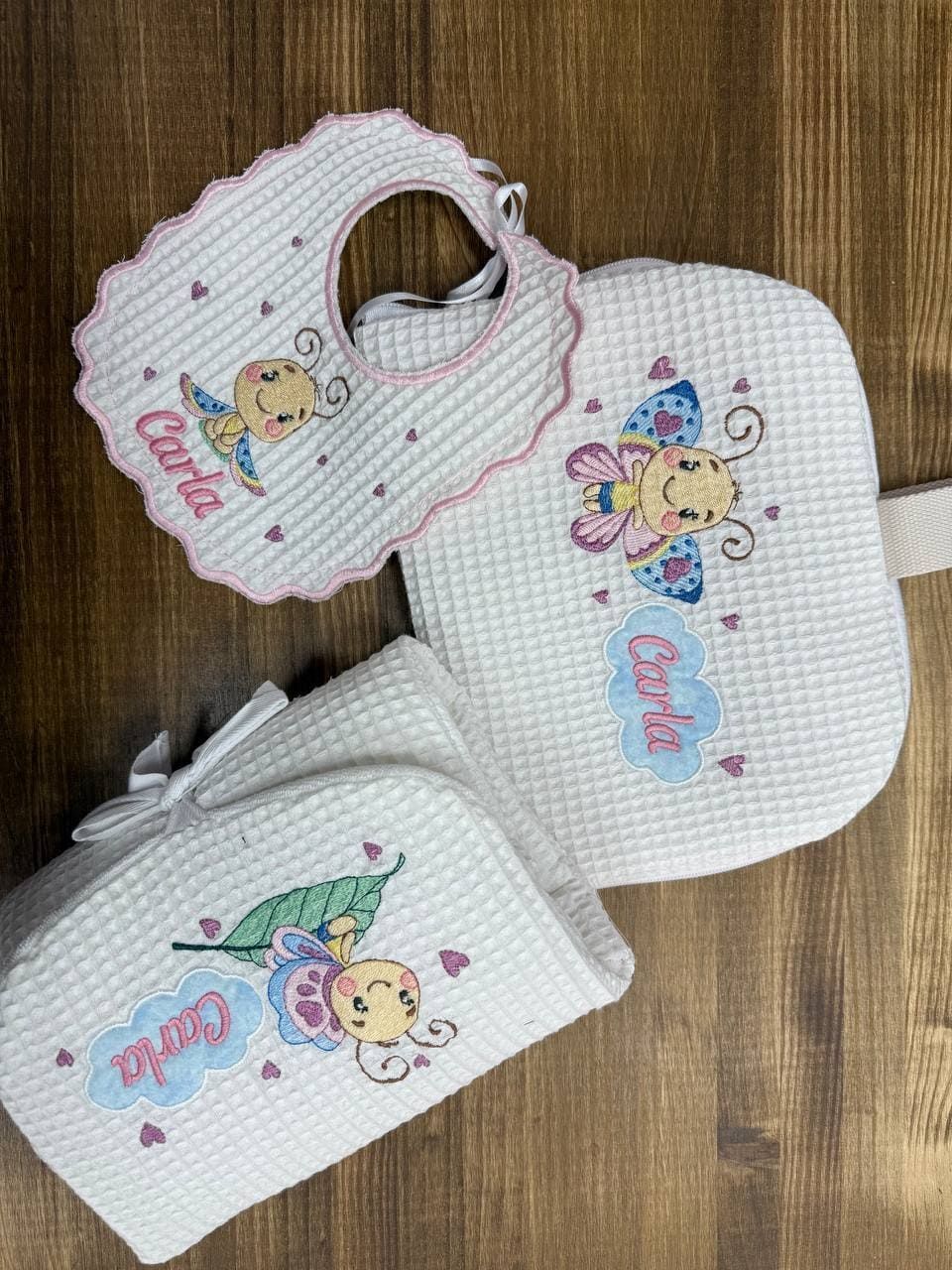 Un babero de bebé y una bolsa de pañales están sobre una mesa de madera.