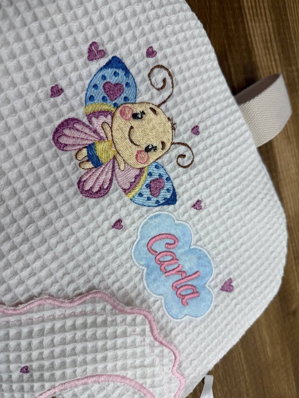 Una manta blanca con una mariposa y el nombre Carla bordado en ella.