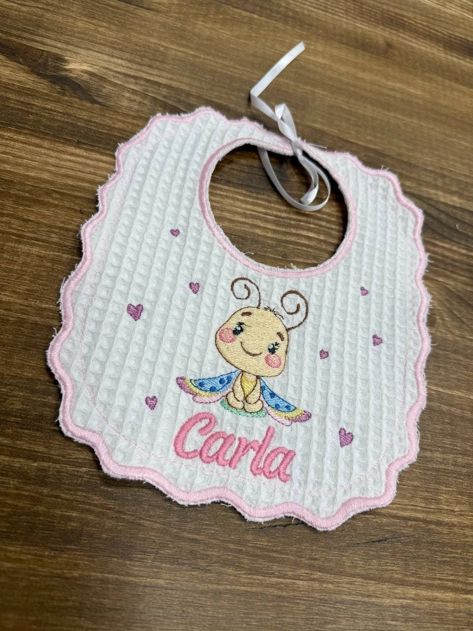 Un babero de bebé con el nombre Carla bordado.