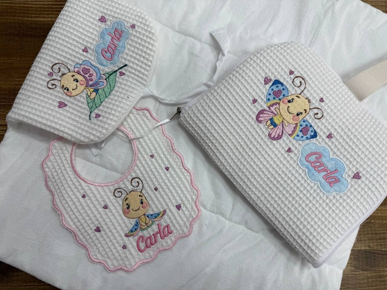 Un babero de bebé y una manta con una mariposa bordada en ellos.