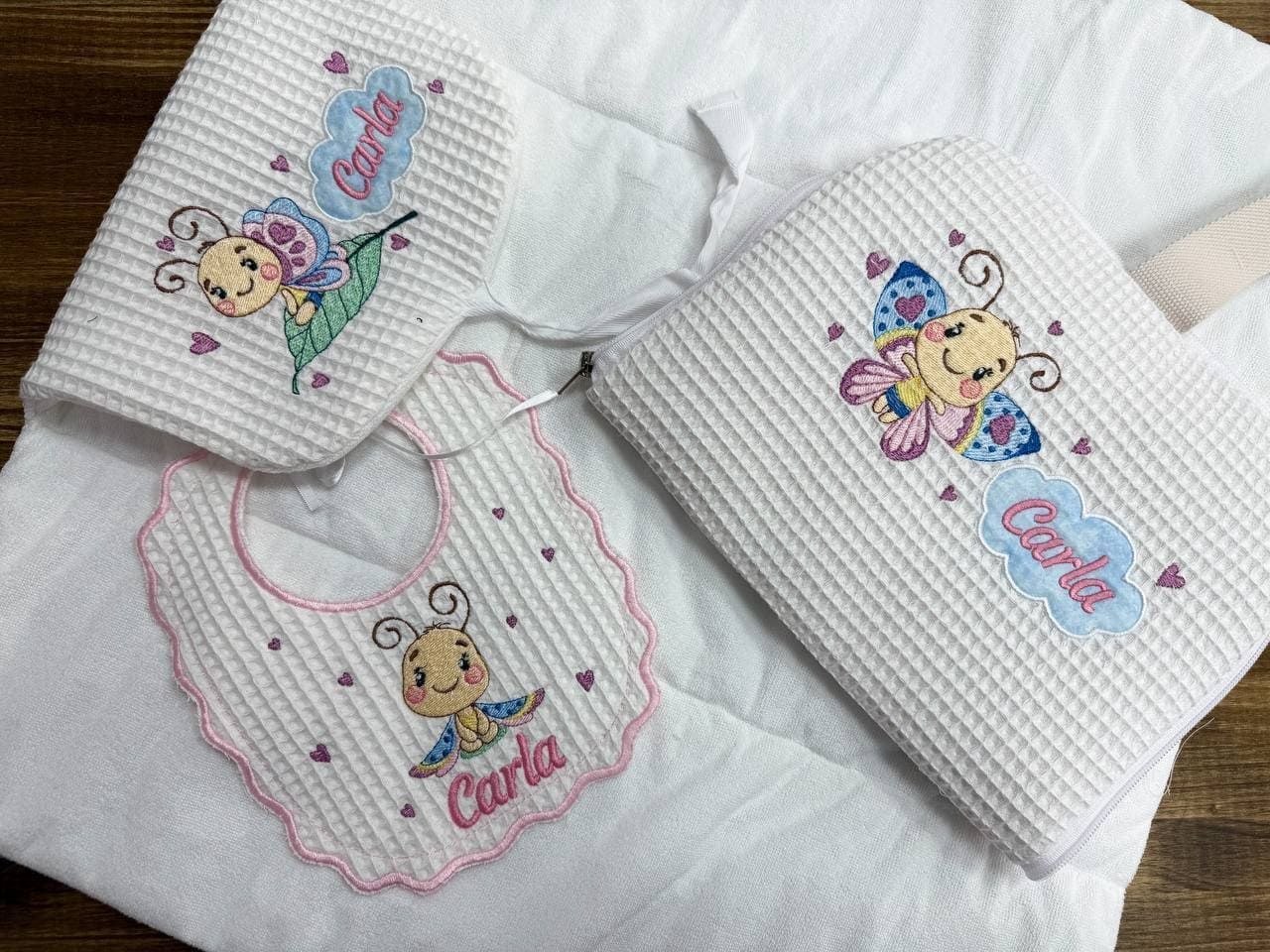 Un babero de bebé y una manta con una mariposa bordada en ellos.