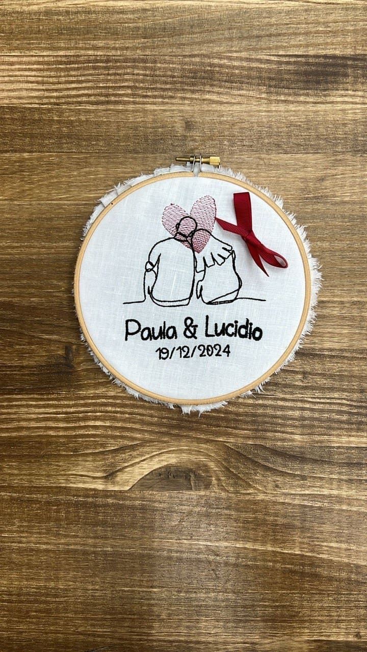 Un bastidor de bordado con dos elefantes y corazones está sobre una mesa de madera.