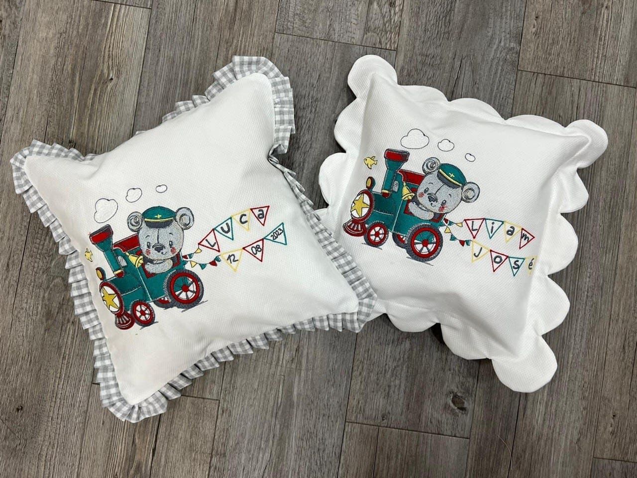 Dos almohadas con un osito de peluche en un tren sobre ellas.
