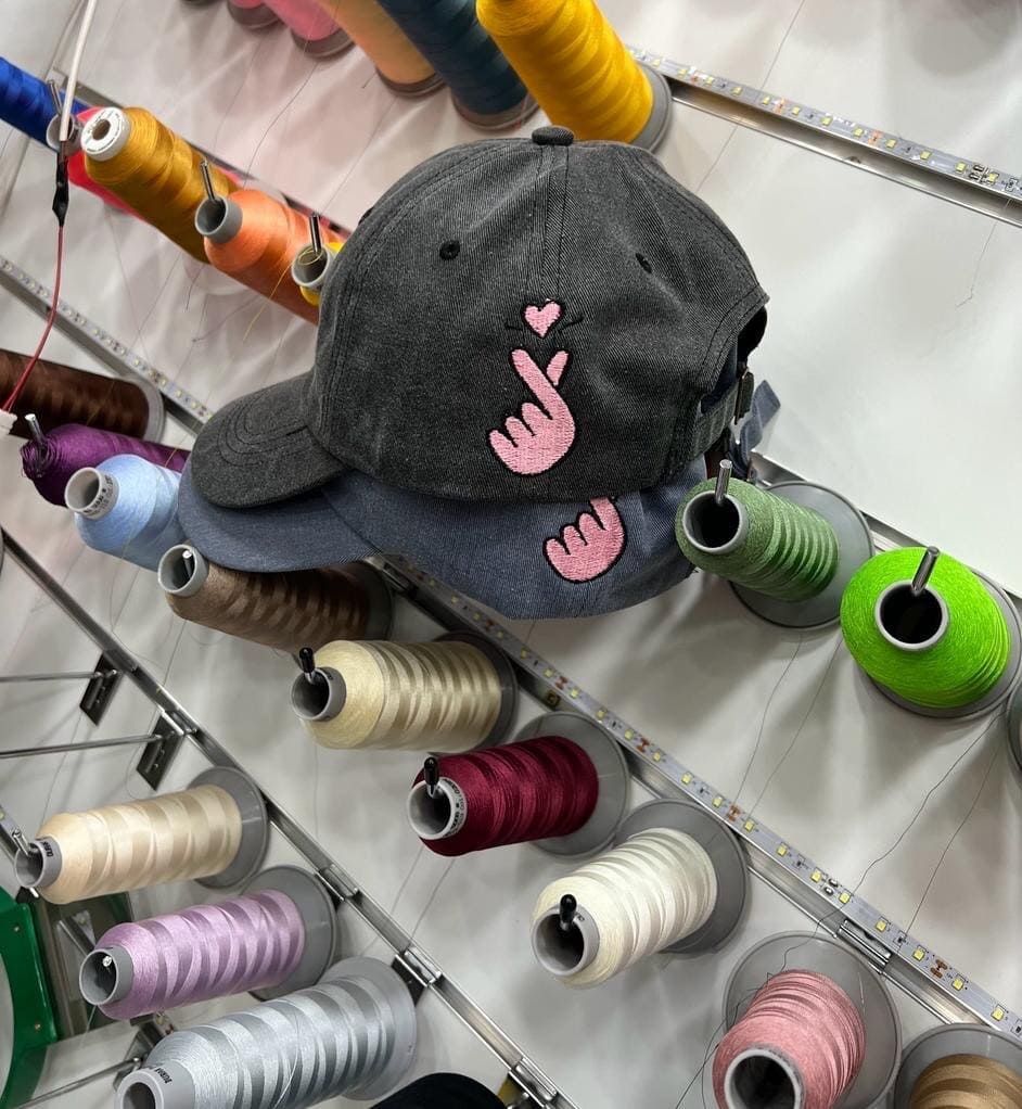 Un sombrero está sobre un estante rodeado de carretes de hilo.