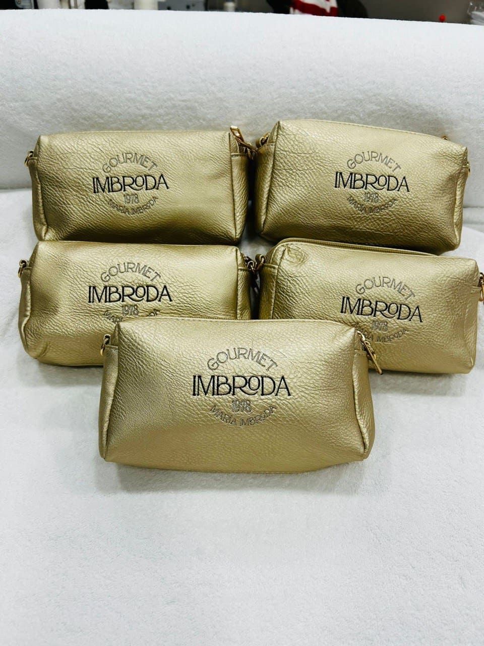 Un grupo de bolsas de cosméticos doradas colocadas una encima de otra sobre una mesa.