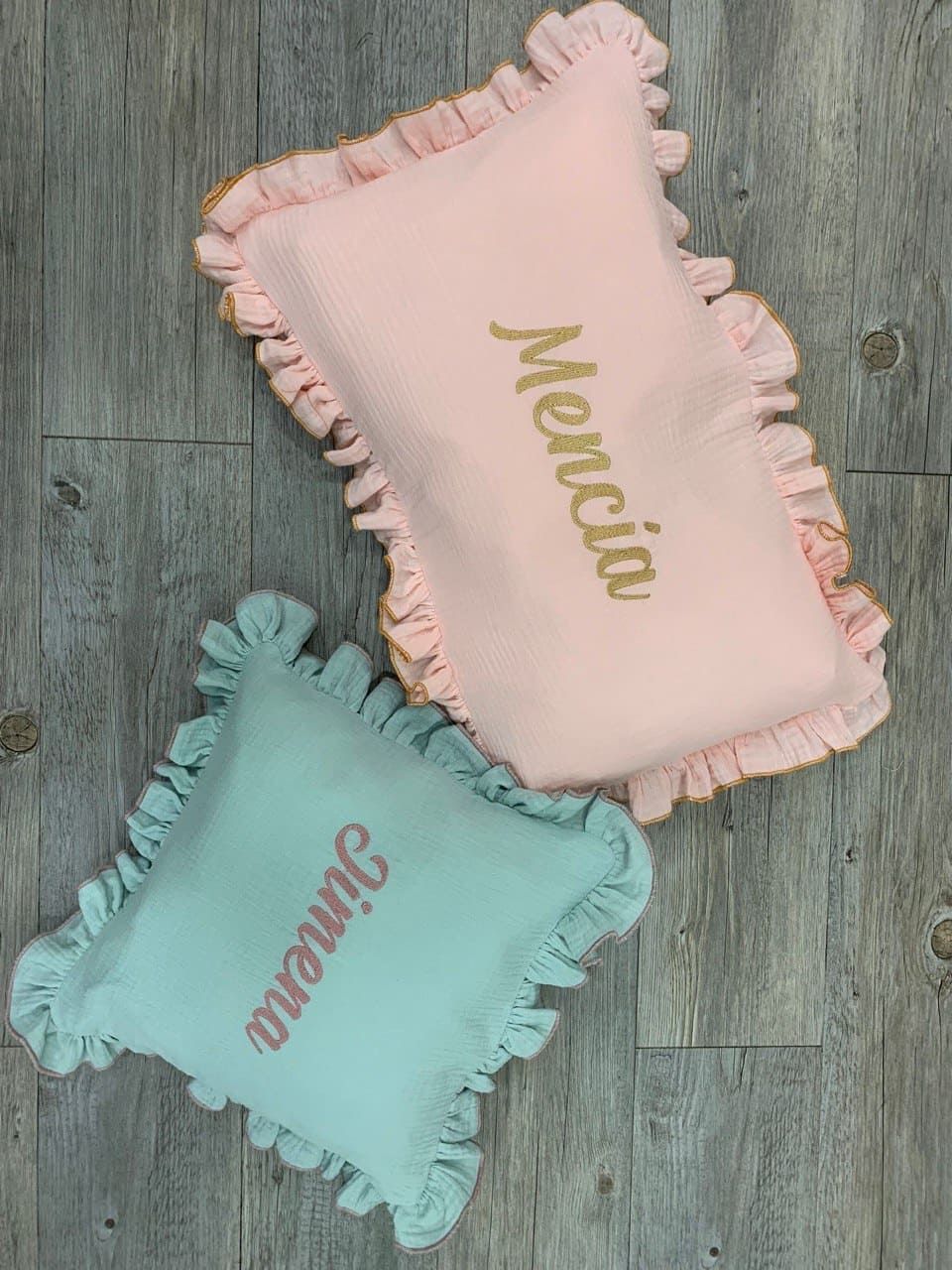 Dos almohadas con nombres están sobre un piso de madera.