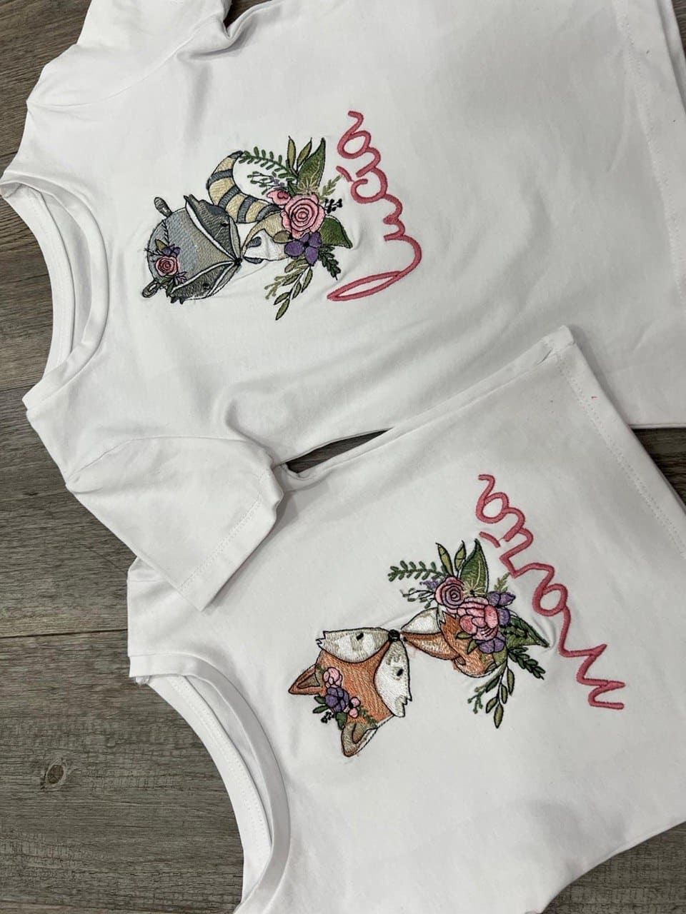 Un par de camisas blancas con un zorro y flores.