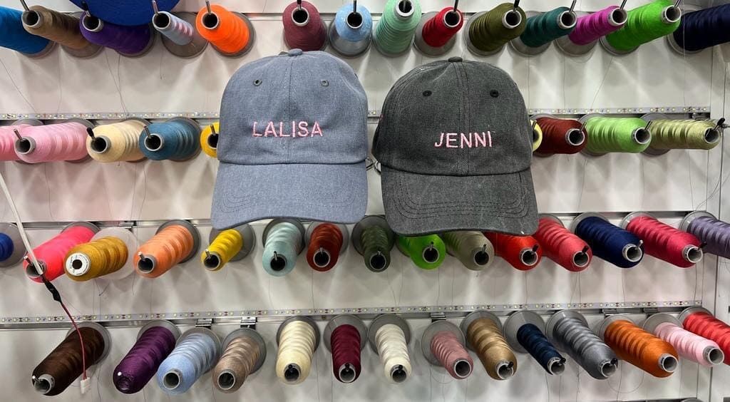 Dos sombreros están sentados en una pared rodeados de carretes de hilo.