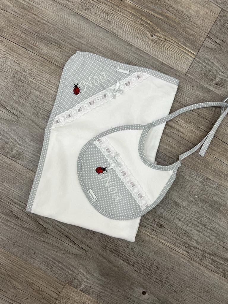 Un babero y una manta de bebé están sobre un suelo de madera.