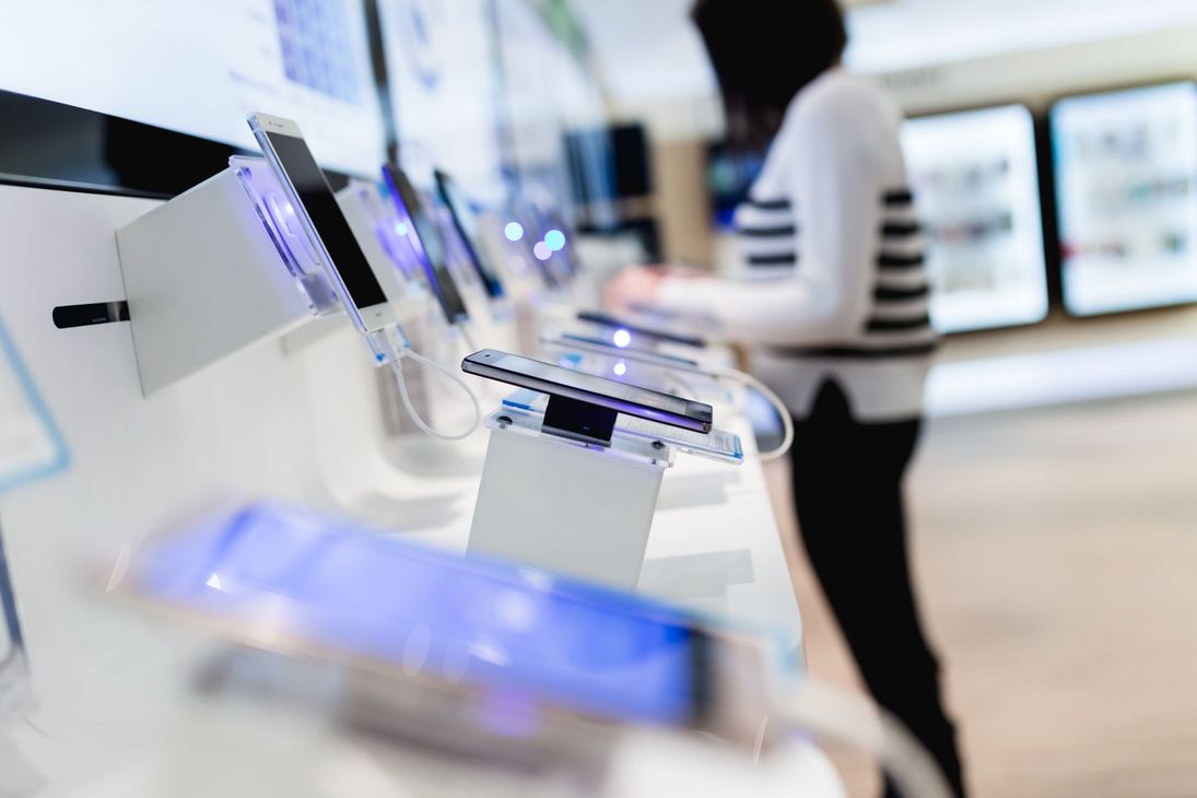 Présentation de Smartphones sur des présentoirs dans un magasin d'électronique lumineux.